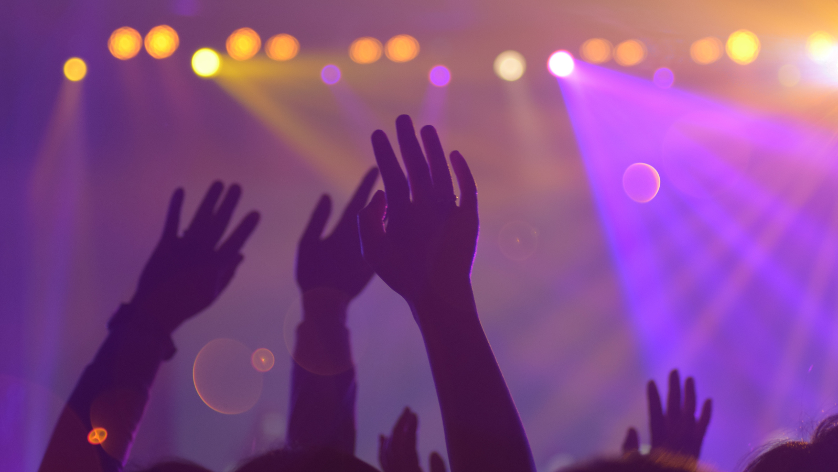 Image of hands waving in the air at a concert.